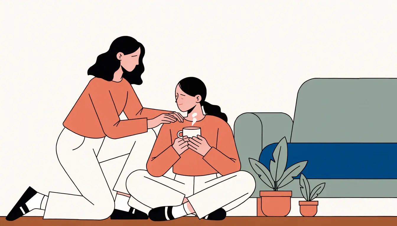 Donna seduta a terra con una tazza calda tra le mani, mentre un'amica le appoggia una mano sulla spalla.